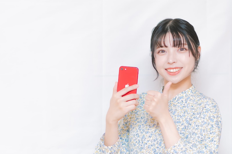 スマホを片手に顎に指をそえる女性